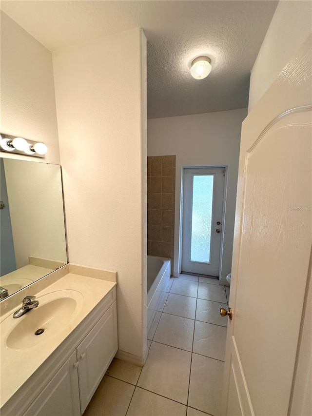 bathroom with a textured ceiling, tile floors, and vanity with extensive cabinet space