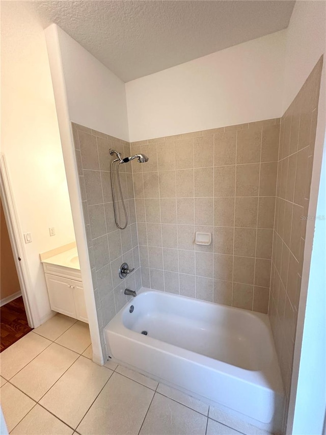 bathroom featuring vanity, a textured ceiling, tile flooring, and tiled shower / bath