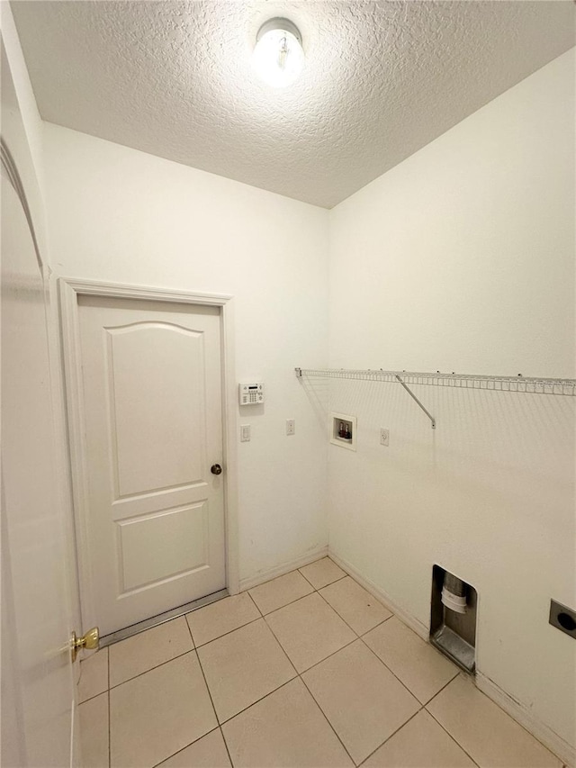 washroom featuring electric dryer hookup, washer hookup, light tile floors, and a textured ceiling