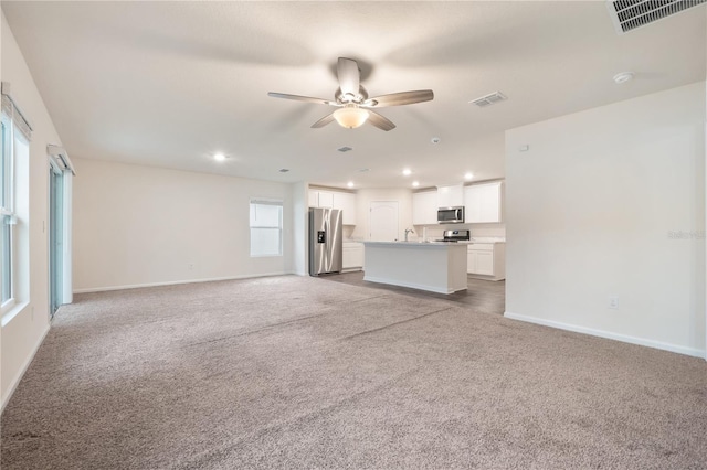 unfurnished living room featuring light carpet and ceiling fan