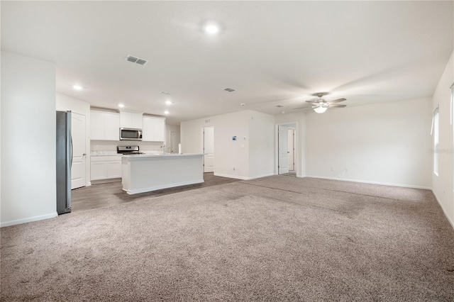 kitchen featuring an island with sink, ceiling fan, stainless steel appliances, white cabinetry, and carpet