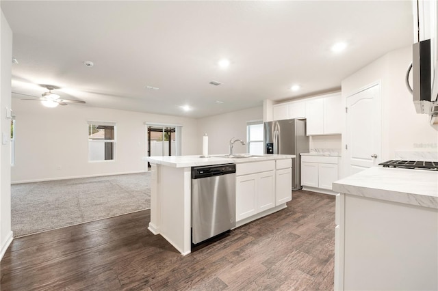 kitchen with dark wood-type flooring, appliances with stainless steel finishes, a center island with sink, white cabinetry, and ceiling fan