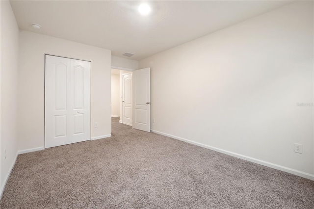 unfurnished bedroom featuring a closet and dark colored carpet