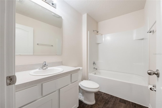 full bathroom featuring bathtub / shower combination, hardwood / wood-style flooring, toilet, vanity, and a textured ceiling