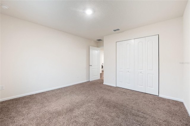 unfurnished bedroom featuring dark carpet and a closet