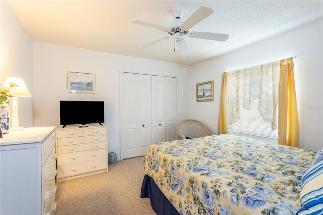 carpeted bedroom with a textured ceiling, a closet, and ceiling fan