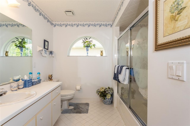 full bathroom featuring shower / bath combination with glass door, tile floors, toilet, and vanity with extensive cabinet space