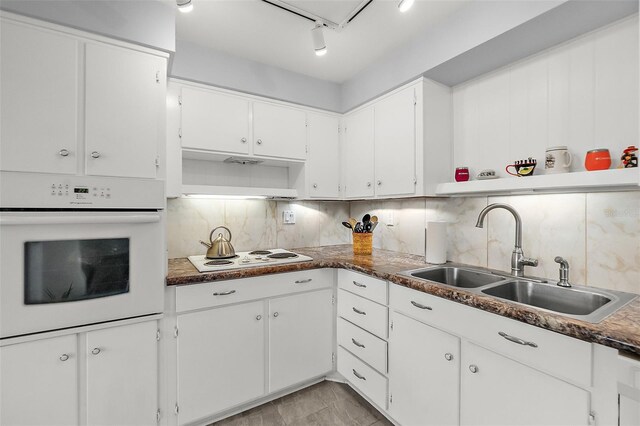 kitchen with white cabinetry, decorative backsplash, white appliances, track lighting, and sink