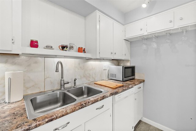 kitchen with tasteful backsplash, dishwasher, sink, light tile patterned floors, and white cabinets