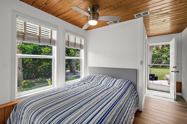 bedroom featuring ceiling fan, multiple windows, light hardwood / wood-style flooring, and wooden ceiling