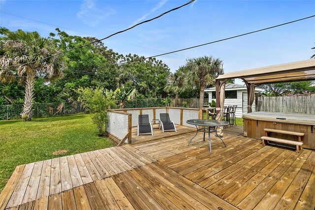 deck with a hot tub and a yard