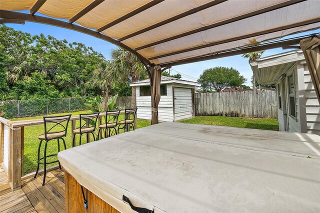 wooden deck with a hot tub, a storage shed, and a lawn