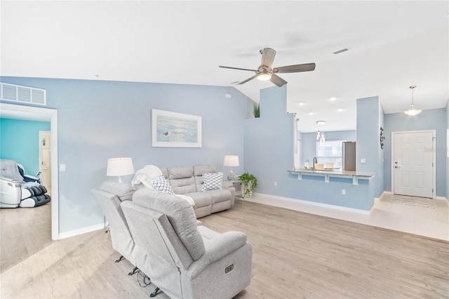 living room featuring sink, light hardwood / wood-style flooring, ceiling fan, and vaulted ceiling