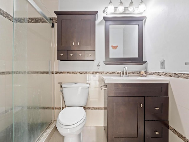 bathroom with vanity, toilet, tile walls, and a shower with door