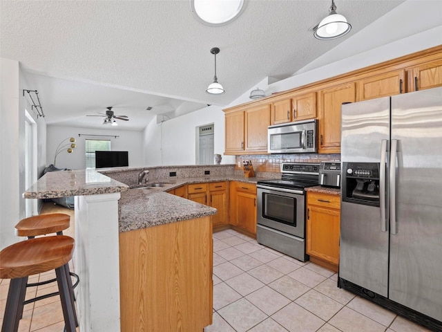 kitchen with a breakfast bar, pendant lighting, appliances with stainless steel finishes, and kitchen peninsula