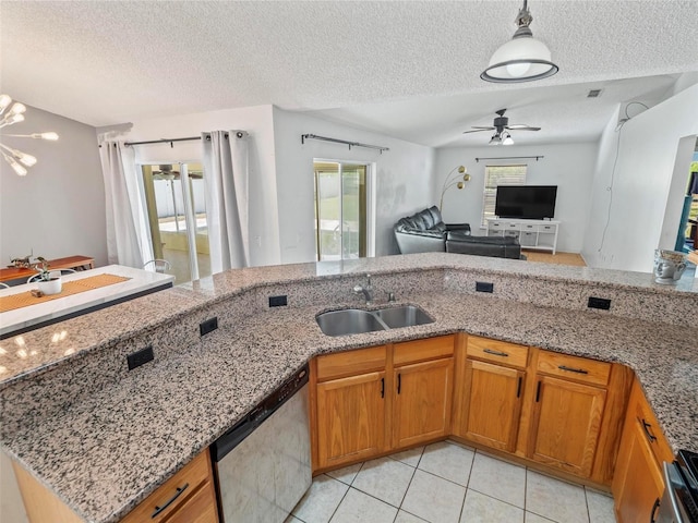 kitchen with light tile patterned floors, dishwasher, a textured ceiling, light stone counters, and sink