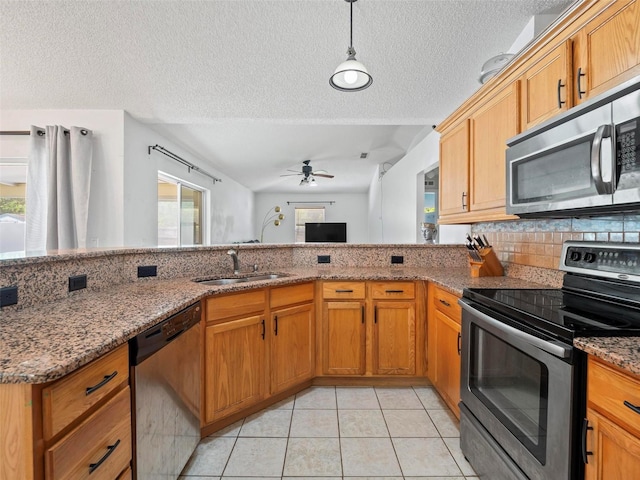 kitchen with kitchen peninsula, sink, light tile patterned flooring, stainless steel appliances, and stone countertops