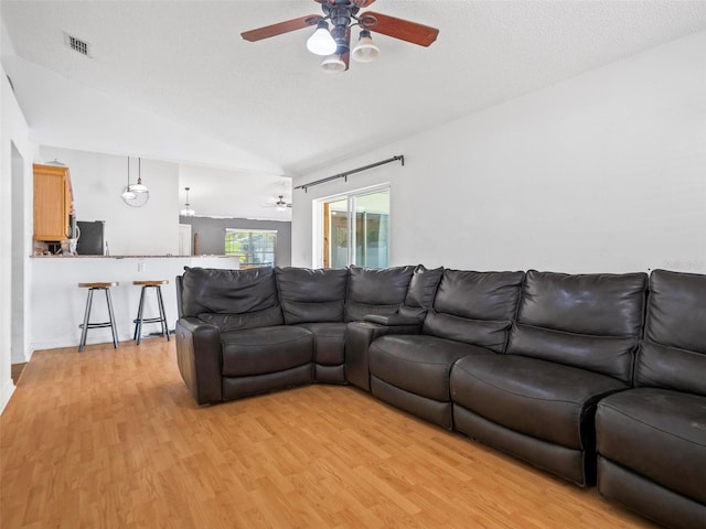 living room featuring lofted ceiling, ceiling fan, a textured ceiling, and light hardwood / wood-style flooring