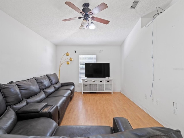 living room featuring light hardwood / wood-style floors, a textured ceiling, and ceiling fan