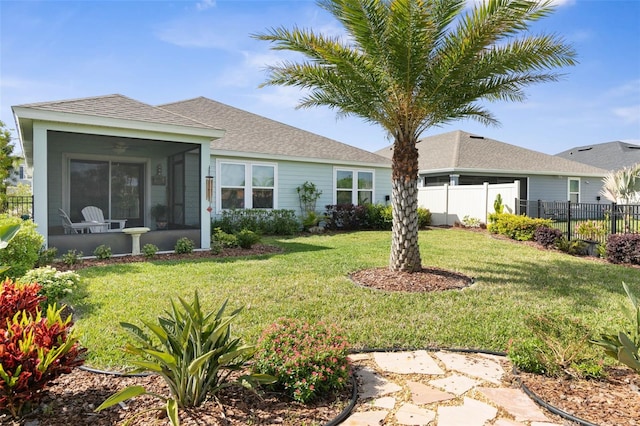 back of house with a yard, a shingled roof, fence, and a sunroom