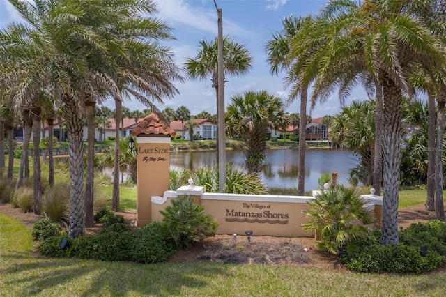 community sign with a water view and a yard