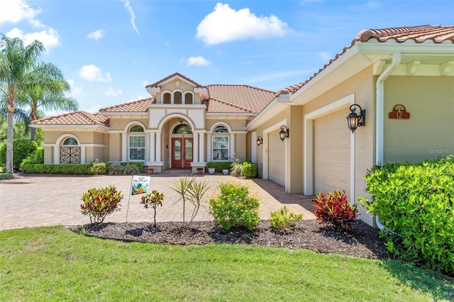 mediterranean / spanish house with a garage and a front lawn