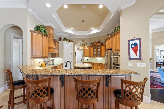 kitchen featuring backsplash, decorative light fixtures, light tile flooring, and a kitchen bar