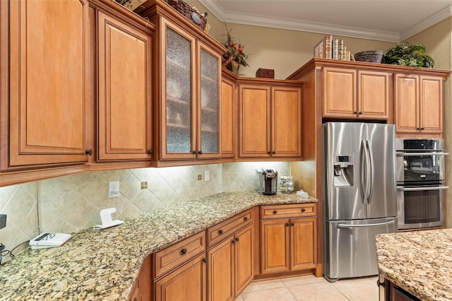 kitchen with light stone counters, appliances with stainless steel finishes, backsplash, light tile flooring, and ornamental molding