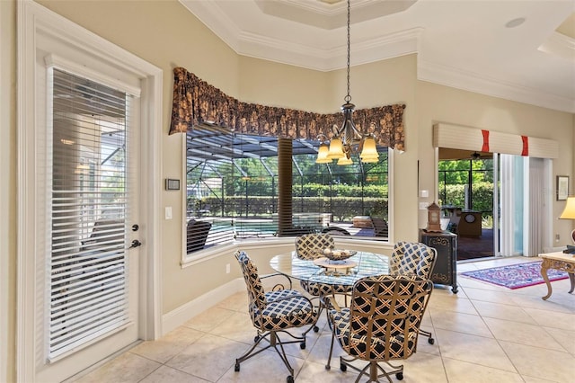 dining area with a raised ceiling, ornamental molding, light tile floors, and a chandelier