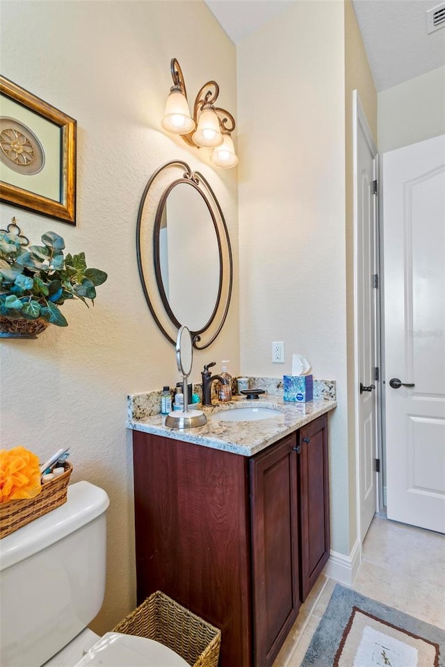 bathroom featuring tile floors, vanity, and toilet