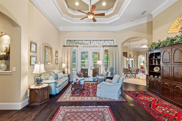 living room with french doors, crown molding, dark hardwood / wood-style flooring, ceiling fan with notable chandelier, and a high ceiling