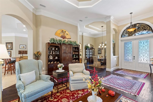 entrance foyer with french doors, ornamental molding, a notable chandelier, hardwood / wood-style flooring, and a high ceiling