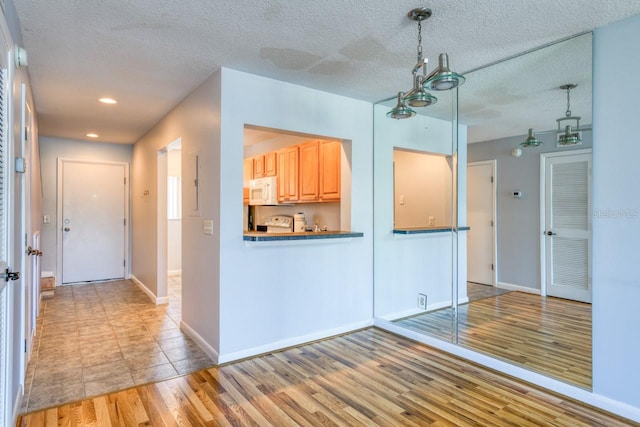 interior space with light brown cabinetry, hanging light fixtures, a textured ceiling, and light tile flooring