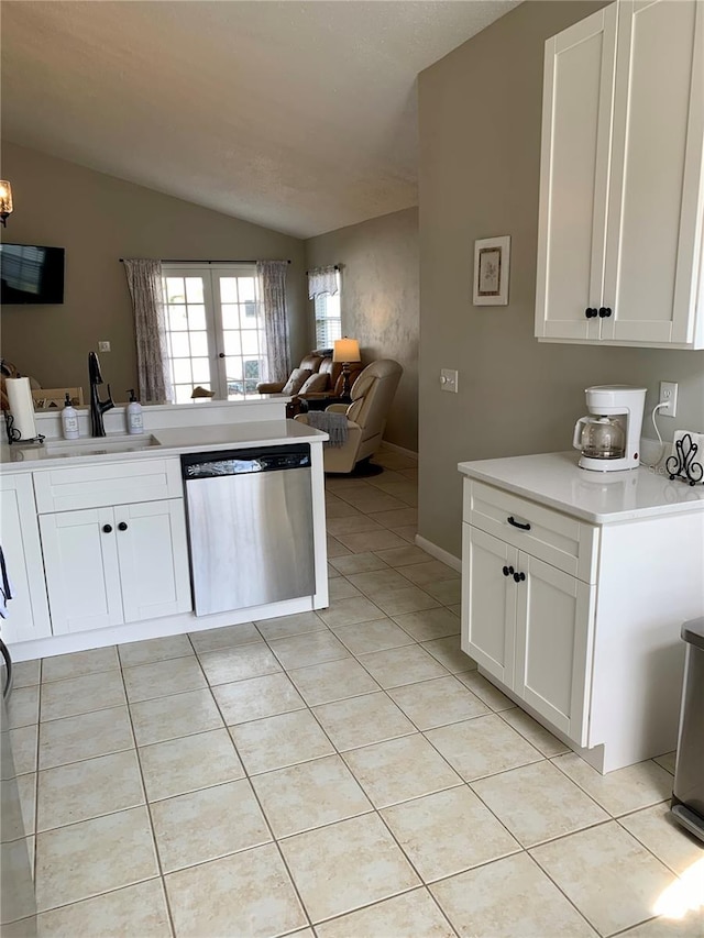 kitchen with white cabinets, stainless steel dishwasher, vaulted ceiling, and sink