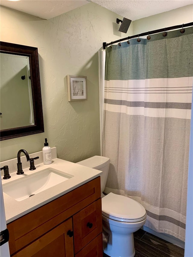 bathroom with toilet, a shower with shower curtain, vanity, and a textured ceiling