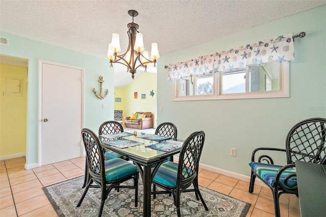 tiled dining space with a textured ceiling and a notable chandelier