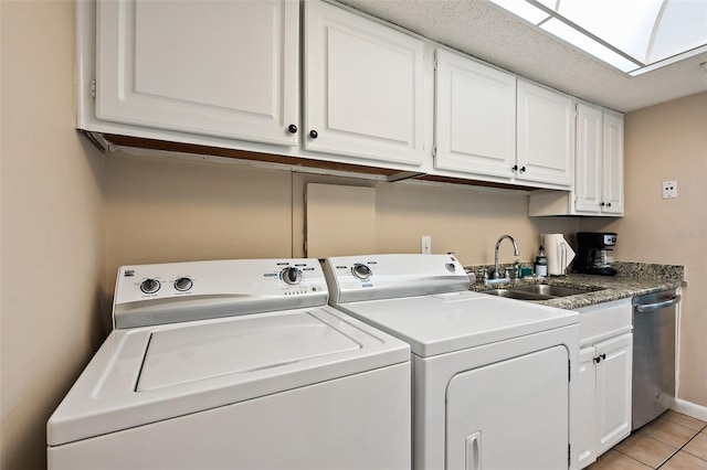 washroom with separate washer and dryer, light tile flooring, a textured ceiling, a skylight, and sink