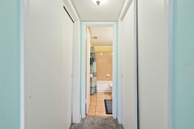 corridor featuring a textured ceiling and light tile floors