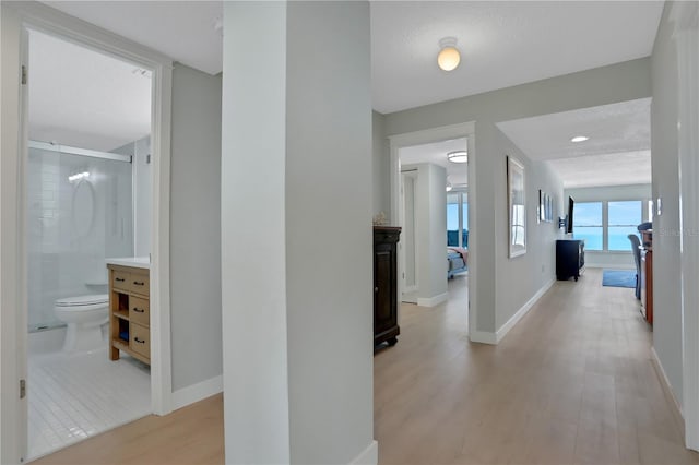 hall featuring light hardwood / wood-style flooring and a textured ceiling