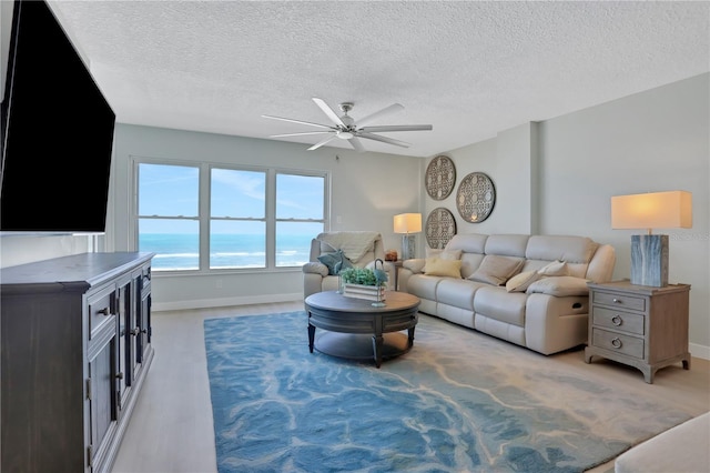 living room with light carpet, ceiling fan, a textured ceiling, and a water view