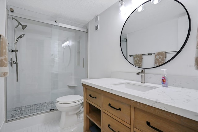 bathroom with tile flooring, a textured ceiling, toilet, a shower with shower door, and vanity