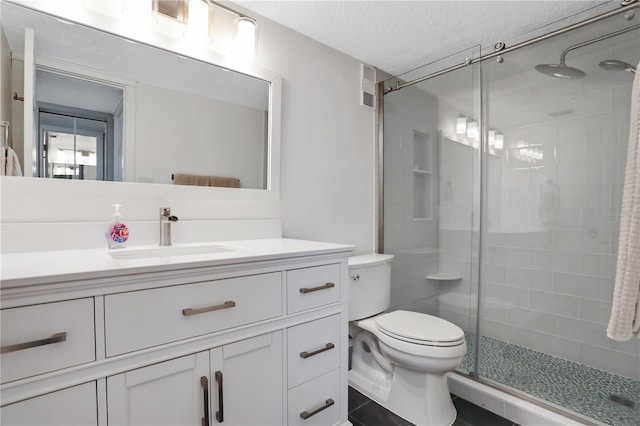 bathroom featuring walk in shower, toilet, vanity with extensive cabinet space, tile flooring, and a textured ceiling