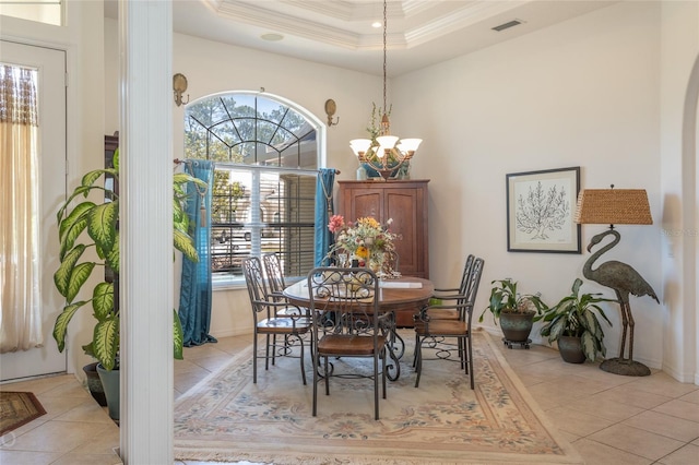 tiled dining area with a raised ceiling and a chandelier