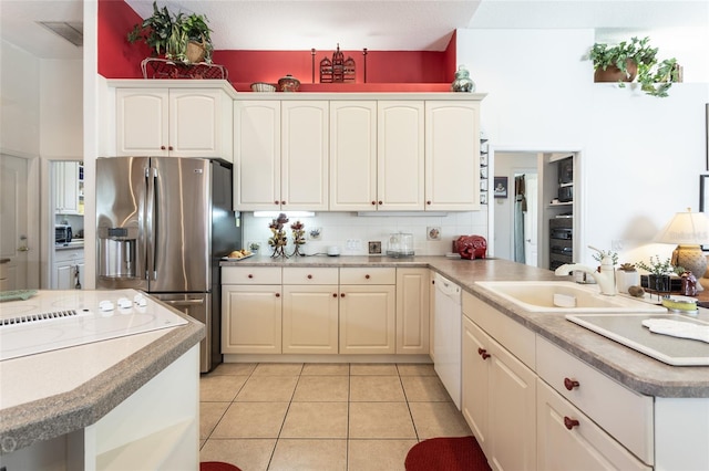 kitchen with light tile floors, sink, tasteful backsplash, stainless steel fridge, and kitchen peninsula