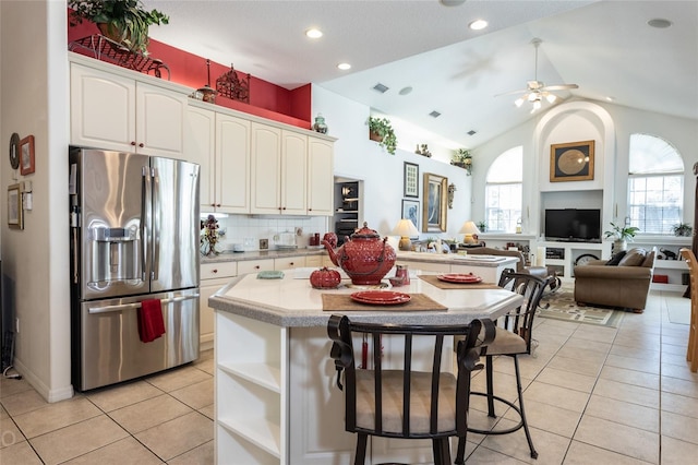 kitchen featuring white cabinets, a kitchen island, tasteful backsplash, stainless steel fridge, and ceiling fan