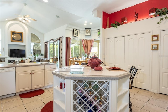 kitchen with white dishwasher, sink, light tile floors, vaulted ceiling, and ceiling fan