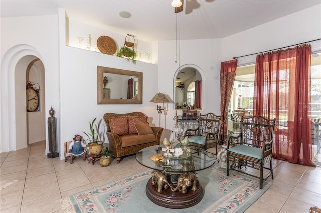 living area featuring lofted ceiling, ceiling fan, and light tile flooring