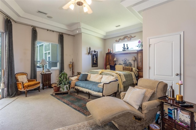 carpeted bedroom featuring ceiling fan and a raised ceiling