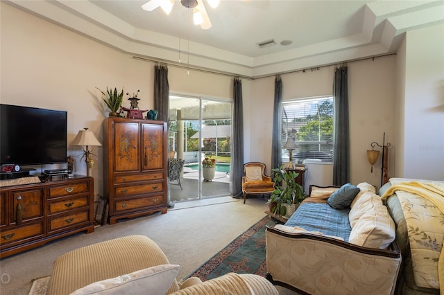 carpeted living room featuring ceiling fan and a tray ceiling