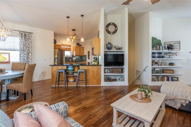 living room featuring ceiling fan with notable chandelier and dark hardwood / wood-style flooring